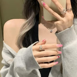 Selfie of a model wearing MyLilith's Barbie press-on nails with a pink ombre design and an accent nail featuring a pink heart, in a medium-length coffin shape.