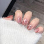 Close-up of a hand wearing MyLilith's pink cat-eye magnetic press-on nails with a glossy finish, featuring an accent nail with a heart design, in a short, squoval shape.