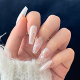 Close-up of a hand wearing MyLilith's press-on nails with a clear and pink base and white marbled design and golden accents, adorned with small rhinestones, in a coffin shape.