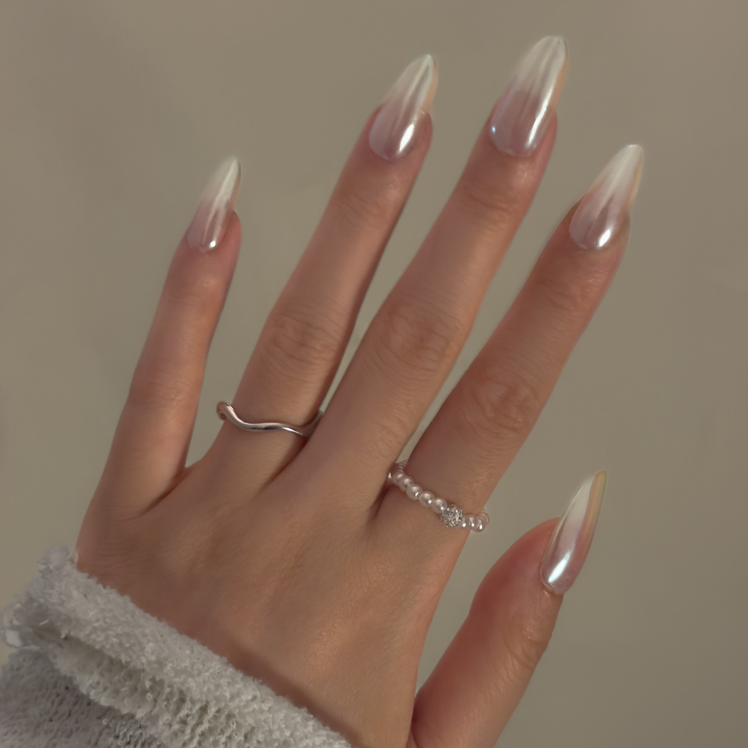 Close-up of a hand wearing MyLilith's Hailey Bieber’s glazed donut style press-on nails, featuring a shiny, pearl-like finish and almond-shaped tips.
