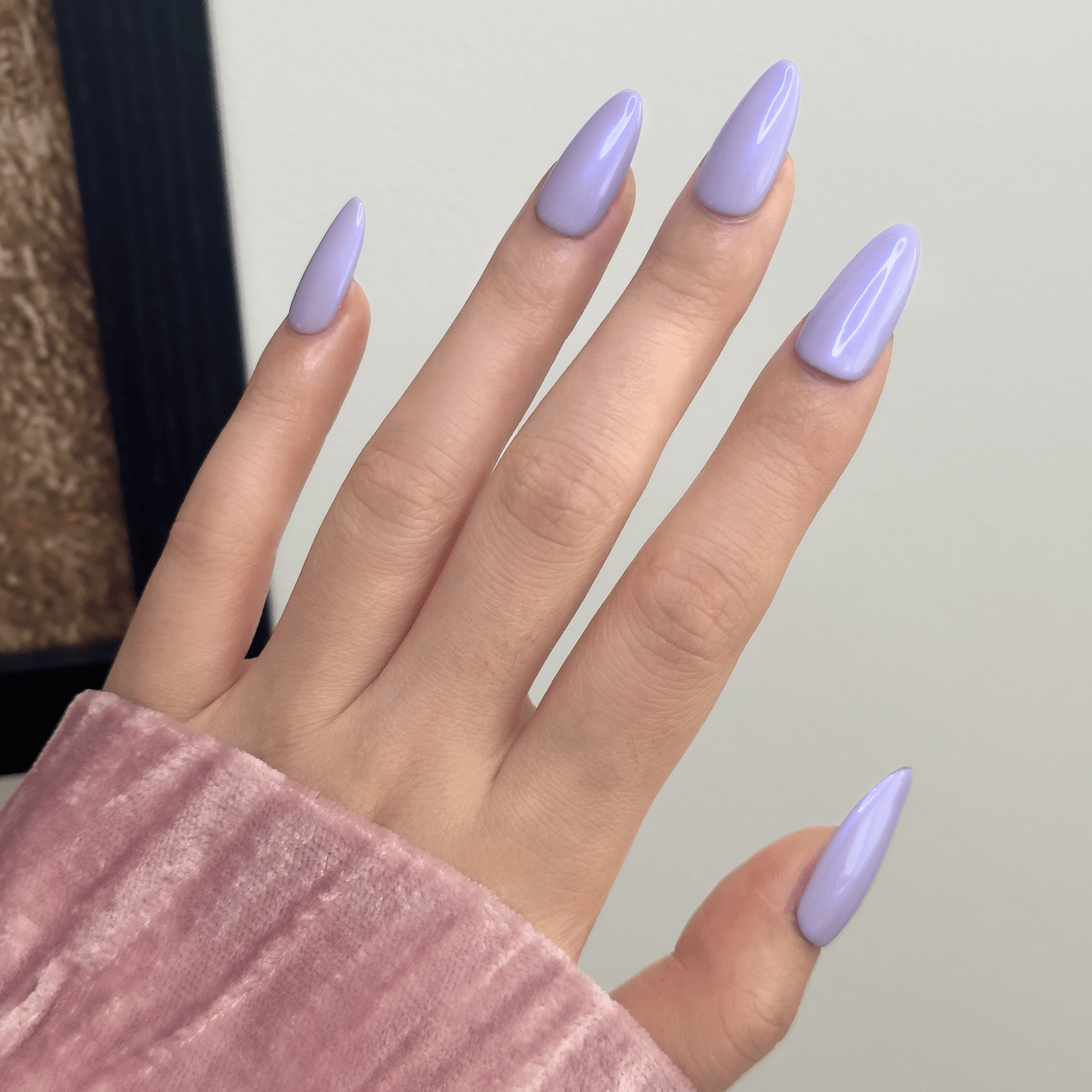 Back-view of a hand wearing MyLilith's purple lavender press-on nails with a glossy glazed finish, giving off blue hues, in a medium-length oval shape.