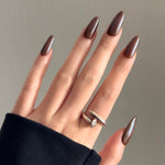 Close-up of a hand wearing MyLilith's glazed chocolate brown press-on nails with a glossy finish, in an oval shape.