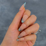 Close-up of a hand wearing MyLilith's press-on nails with a nude base and metallic chrome tips, in an oval shape.