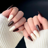 Close-up of two hands wearing MyLilith's chocolate brown and cream white press-on nails with an almond shape.