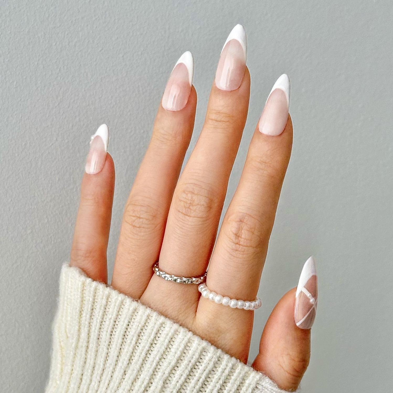 Close-up of a hand wearing MyLilith's French tip Ballerina press-on nails with an almond shape and one accent nail featuring a geometric design.